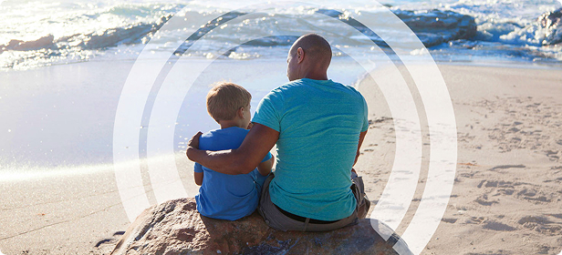 Father and son sit on the beach